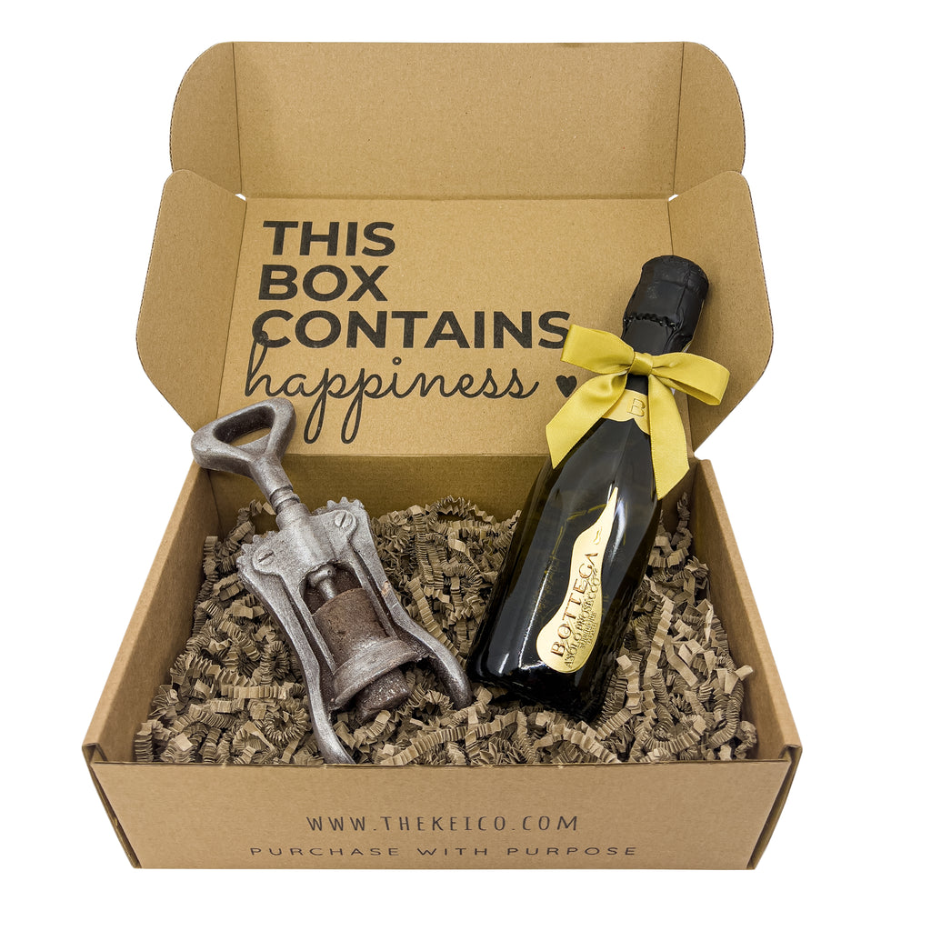 High angle shot of Bottega Poeti Prosecco 20cl and an authentic chocolate corkscrew, nestled in a protective shredded paper within a branded gift box.