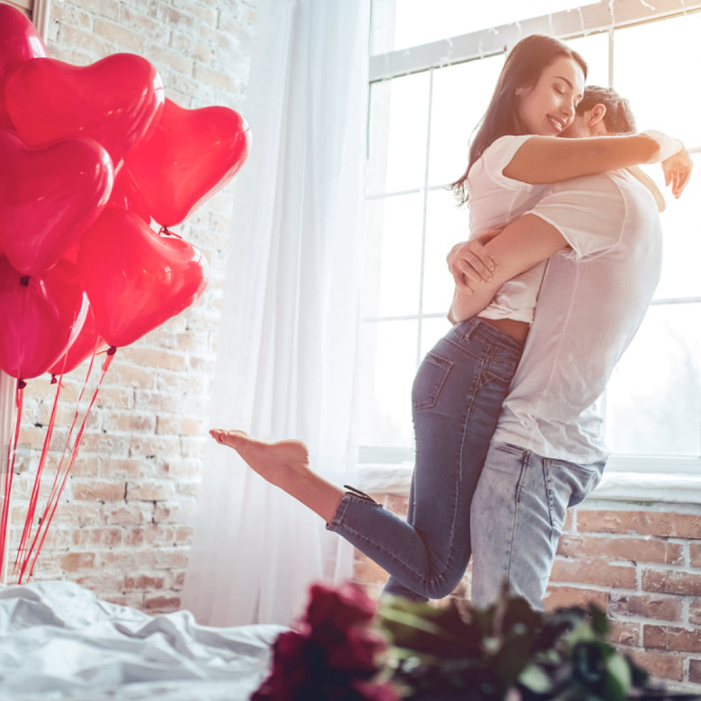 couple hugging with heart shaped balloons in the back