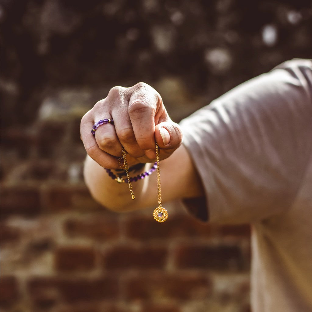 Rose quartz crystal necklace on gold chain, symbolic of love and compassion