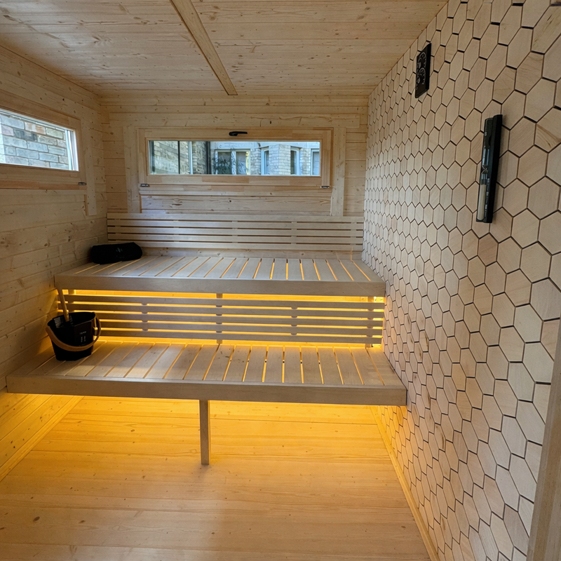 Modern indoor sauna installation with LED bench lighting and feature timber wall, showcasing a premium commercial and residential wellness environment