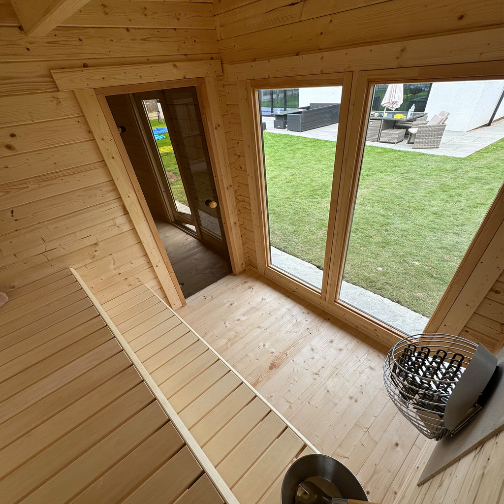 Interior sauna with Nordic Spruce benches, backrests and glazed door—warm, light-filled Nordic heat room.