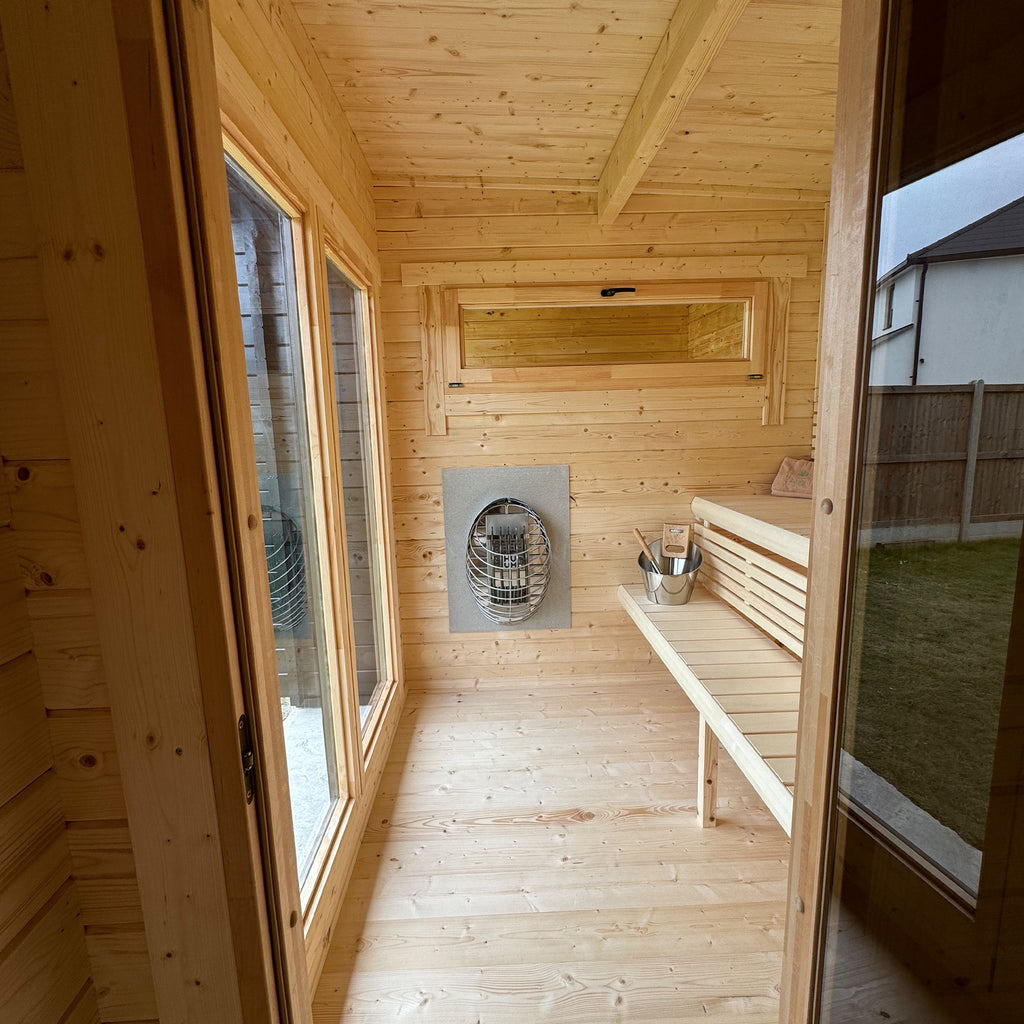 Interior sauna with Nordic Spruce benches, backrests and glazed door—warm, light-filled Nordic heat room.