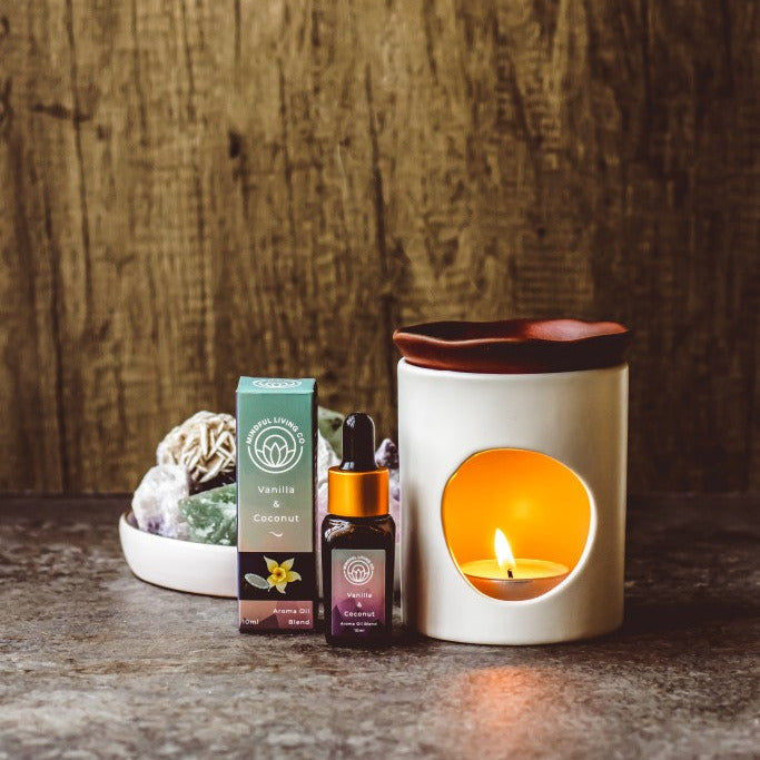 Vanilla & Coconut fragrance oil bottle with coconut pieces and vanilla beans near a candlelit burner – creamy, tropical, and comforting.