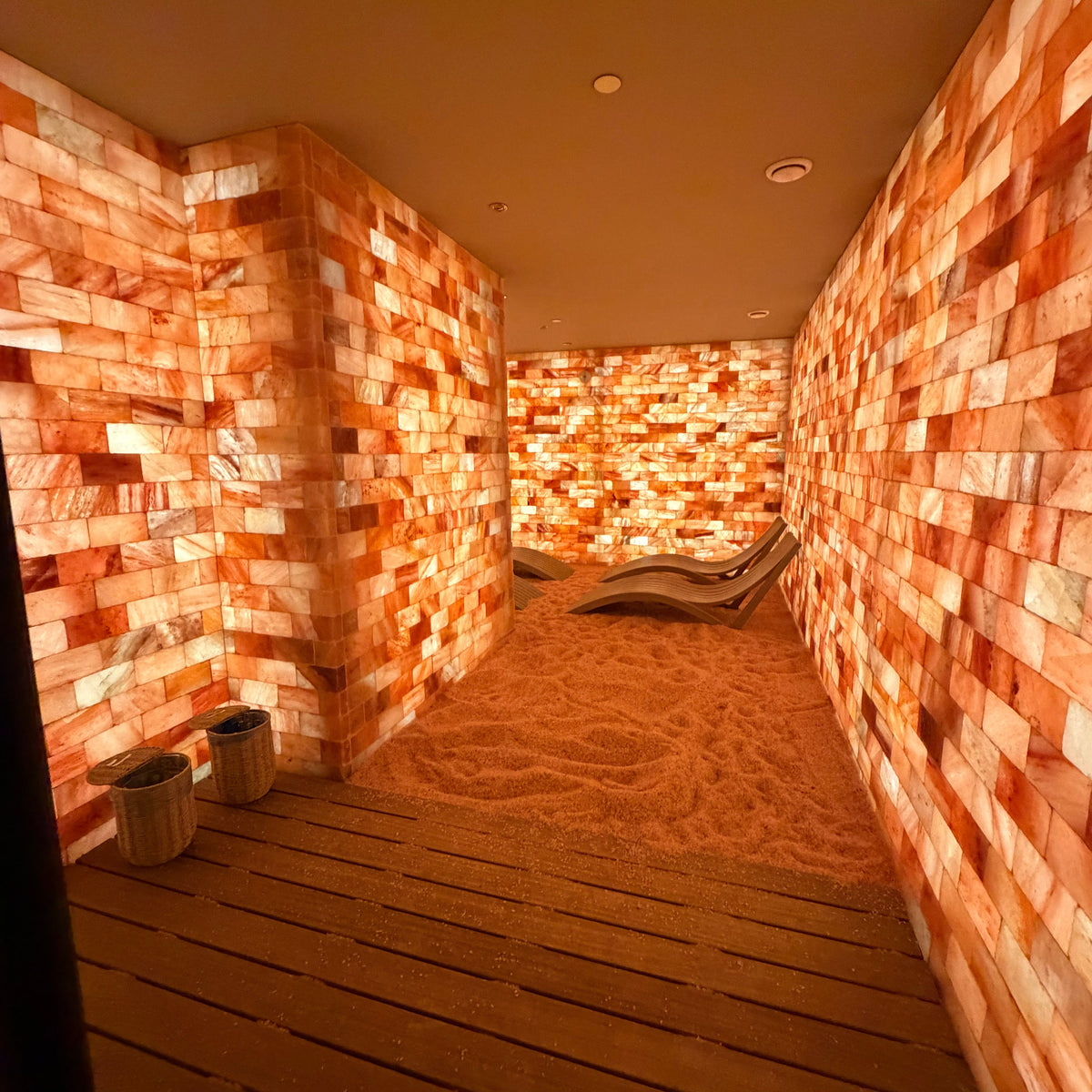 Design reference: salt room layout with illuminated brick walls, a wall return, granular flooring and curved relaxation seating.