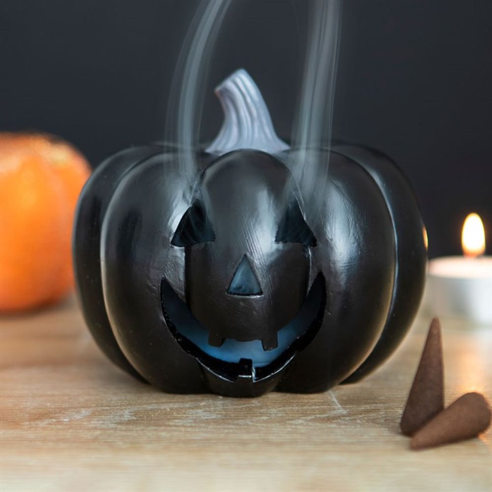 KeiCo's Black Pumpkin Incense Cone Holder, with its enchanting cut-out face design, set against a dark backdrop.